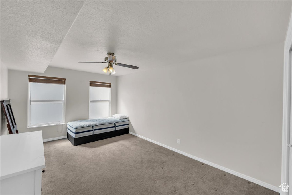 Unfurnished bedroom featuring carpet flooring, a textured ceiling, and ceiling fan