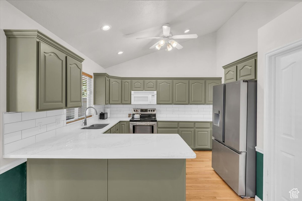 Kitchen featuring stainless steel appliances, sink, kitchen peninsula, vaulted ceiling, and backsplash