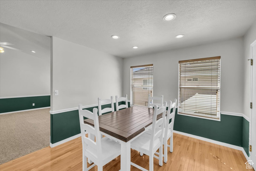 Dining space featuring ceiling fan, hardwood / wood-style floors, and a textured ceiling