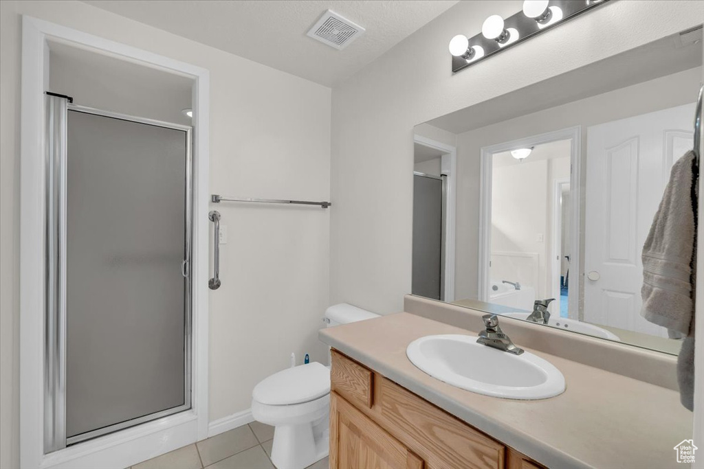 Bathroom with tile patterned flooring, a shower with door, and vanity