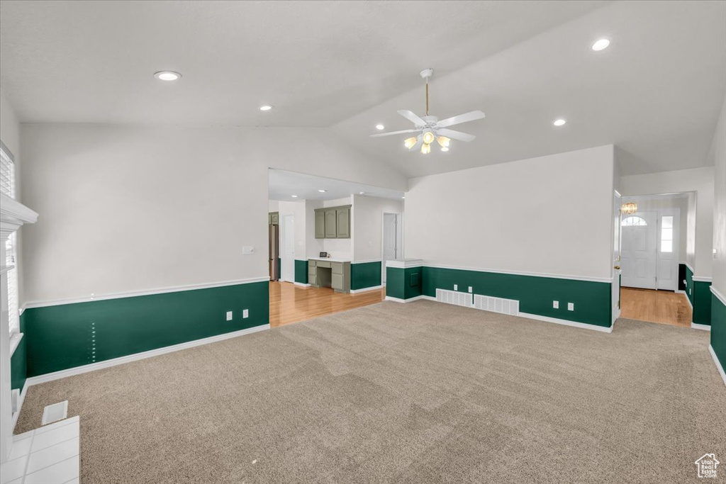 Carpeted living room with lofted ceiling and ceiling fan