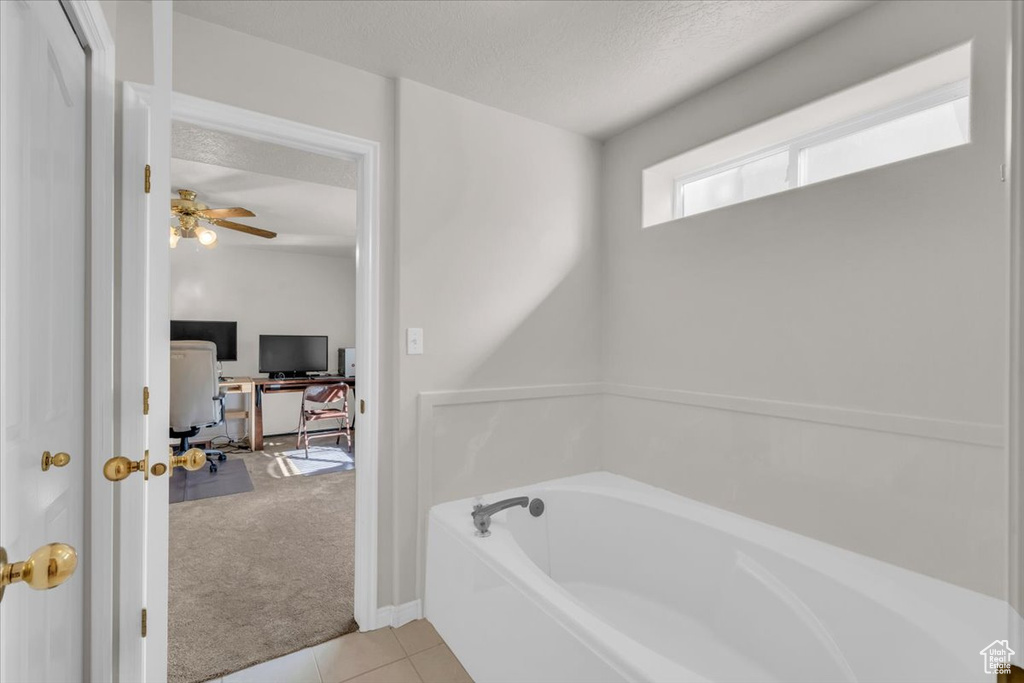 Bathroom featuring ceiling fan, tile patterned floors, a textured ceiling, and a bathing tub