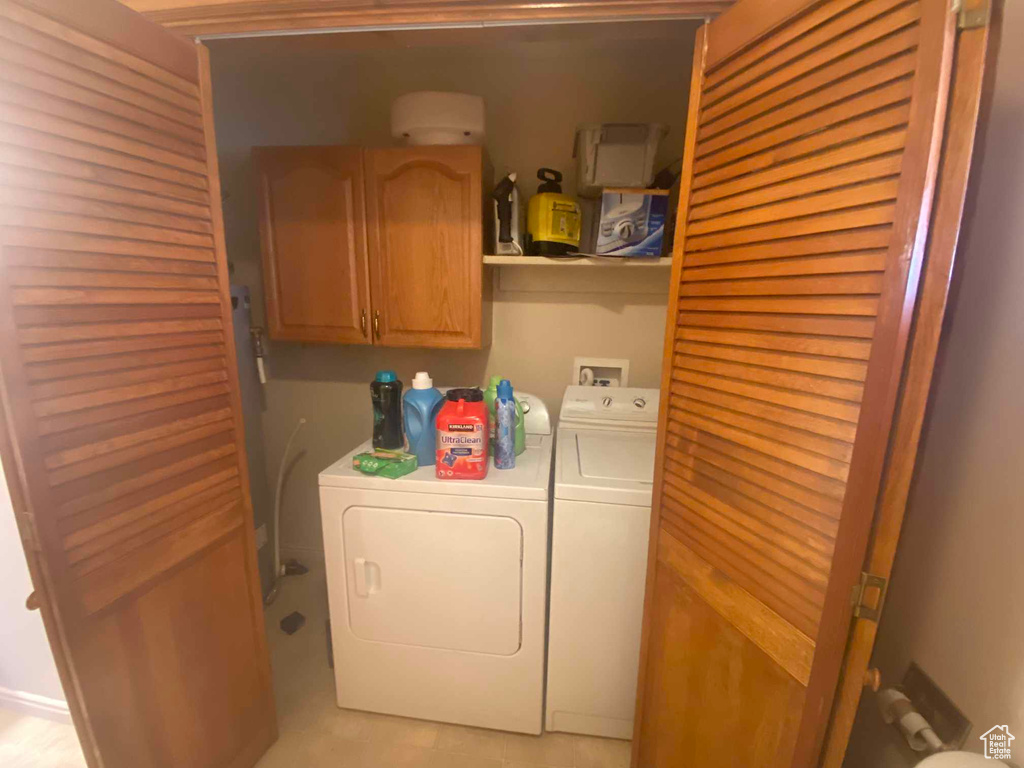 Laundry room featuring separate washer and dryer and cabinets