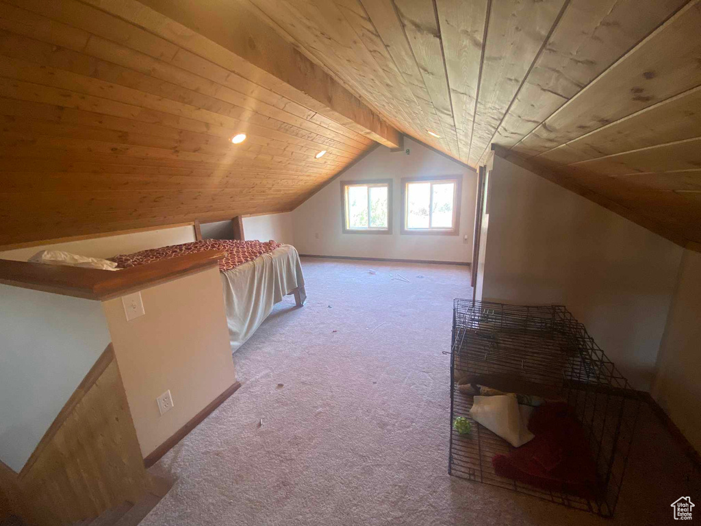 Additional living space with light colored carpet, vaulted ceiling with beams, and wood ceiling