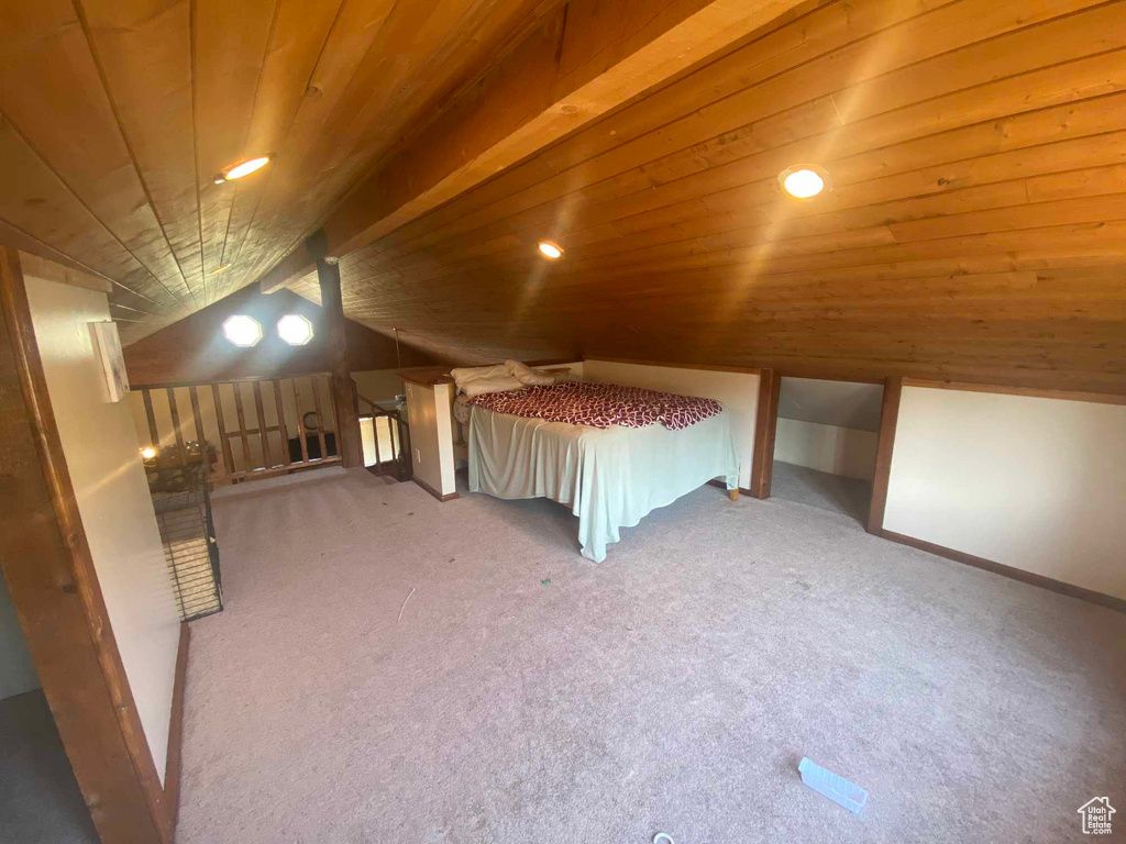 Unfurnished bedroom with carpet, wooden ceiling, and vaulted ceiling with beams