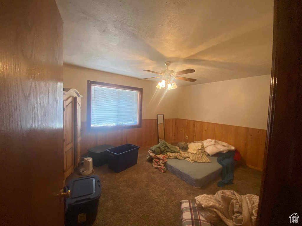 Interior space with a textured ceiling, wooden walls, and ceiling fan