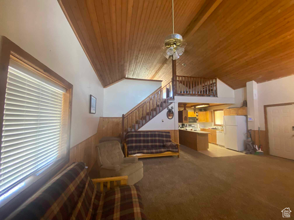 Carpeted living room with ceiling fan, wood walls, vaulted ceiling, and wood ceiling