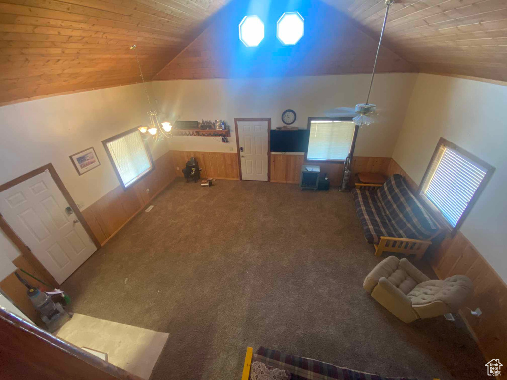 Living room featuring ceiling fan, wooden walls, wood ceiling, and high vaulted ceiling