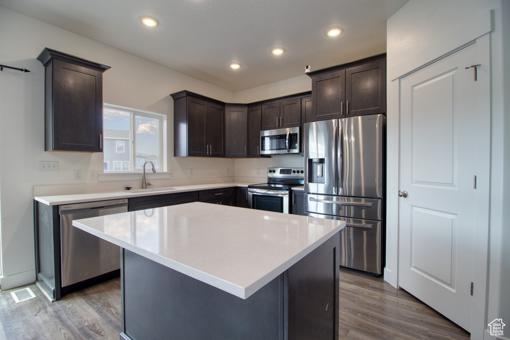 Kitchen featuring hardwood / wood-style floors, appliances with stainless steel finishes, sink, and a center island