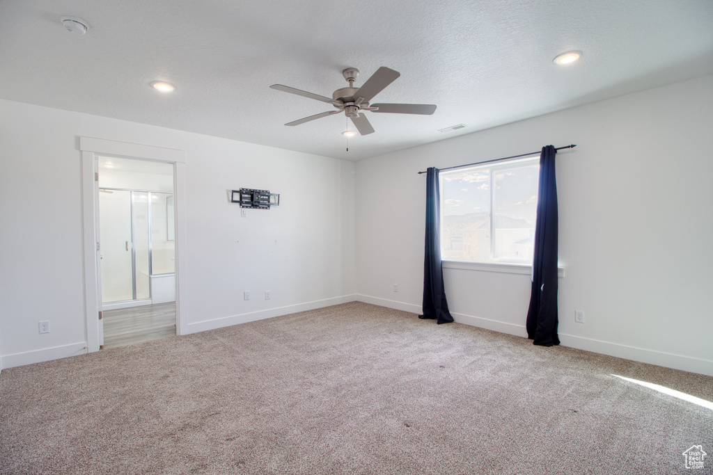 Spare room with light colored carpet, a textured ceiling, and ceiling fan