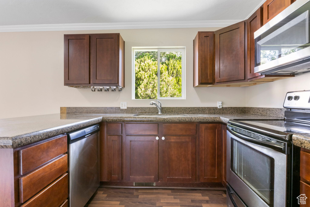 Kitchen featuring stainless steel appliances, sink, dark hardwood / wood-style flooring, kitchen peninsula, and ornamental molding