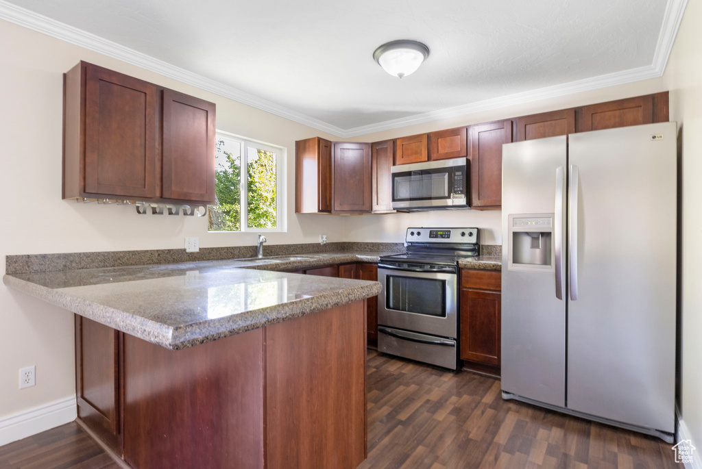 Kitchen with dark hardwood / wood-style floors, ornamental molding, kitchen peninsula, appliances with stainless steel finishes, and stone counters