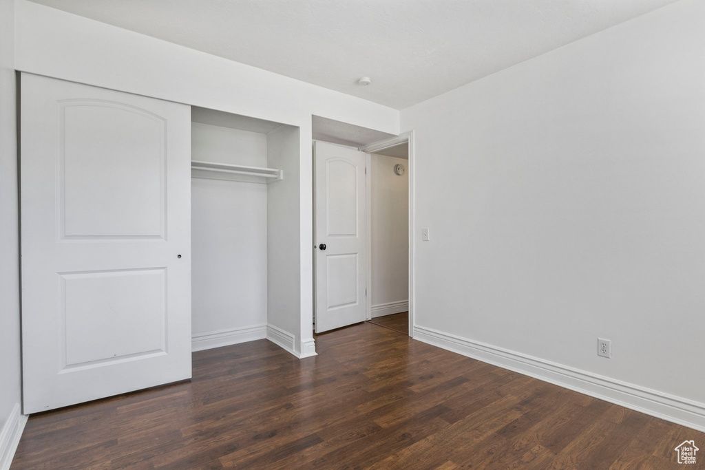 Unfurnished bedroom with dark wood-type flooring and a closet