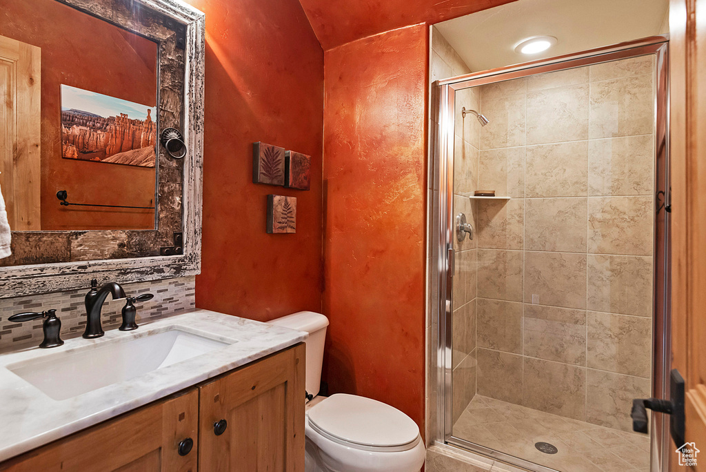 Bathroom featuring walk in shower, vanity, toilet, and tasteful backsplash