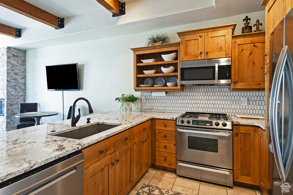 Kitchen featuring beamed ceiling, light stone countertops, sink, appliances with stainless steel finishes, and backsplash