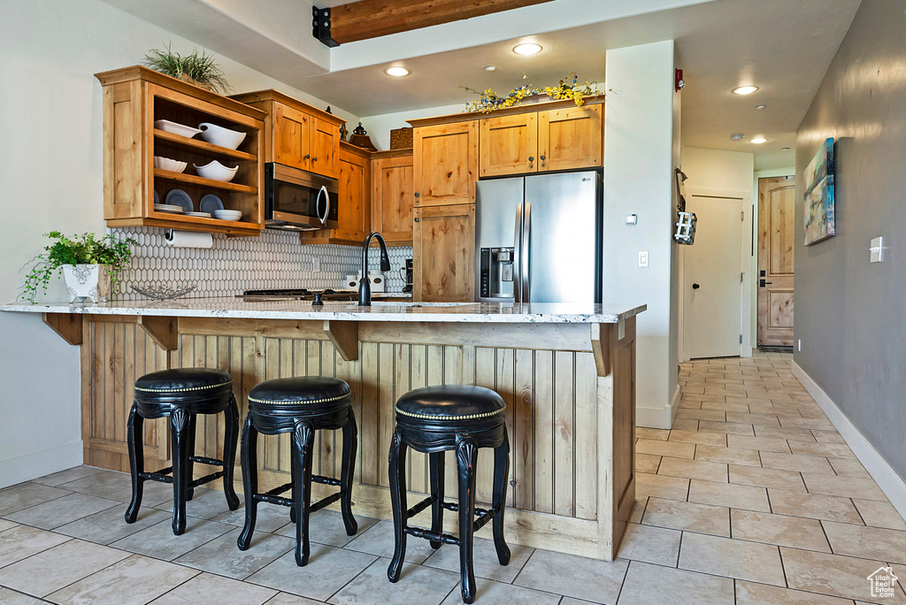 Kitchen with a breakfast bar area, sink, stainless steel appliances, kitchen peninsula, and backsplash