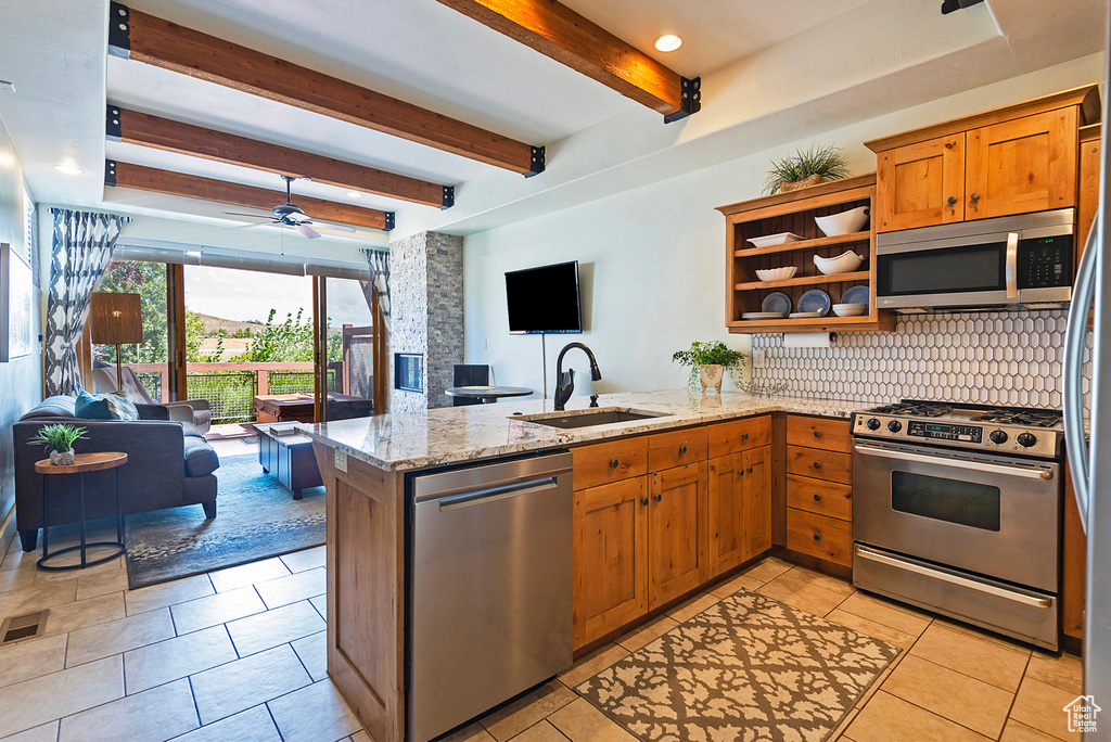 Kitchen featuring appliances with stainless steel finishes, kitchen peninsula, beam ceiling, and sink