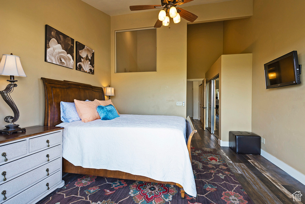 Bedroom with ceiling fan, dark hardwood / wood-style flooring, and a high ceiling