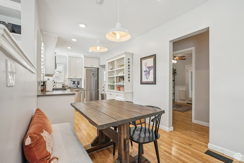 Dining space with light hardwood / wood-style flooring and ceiling fan