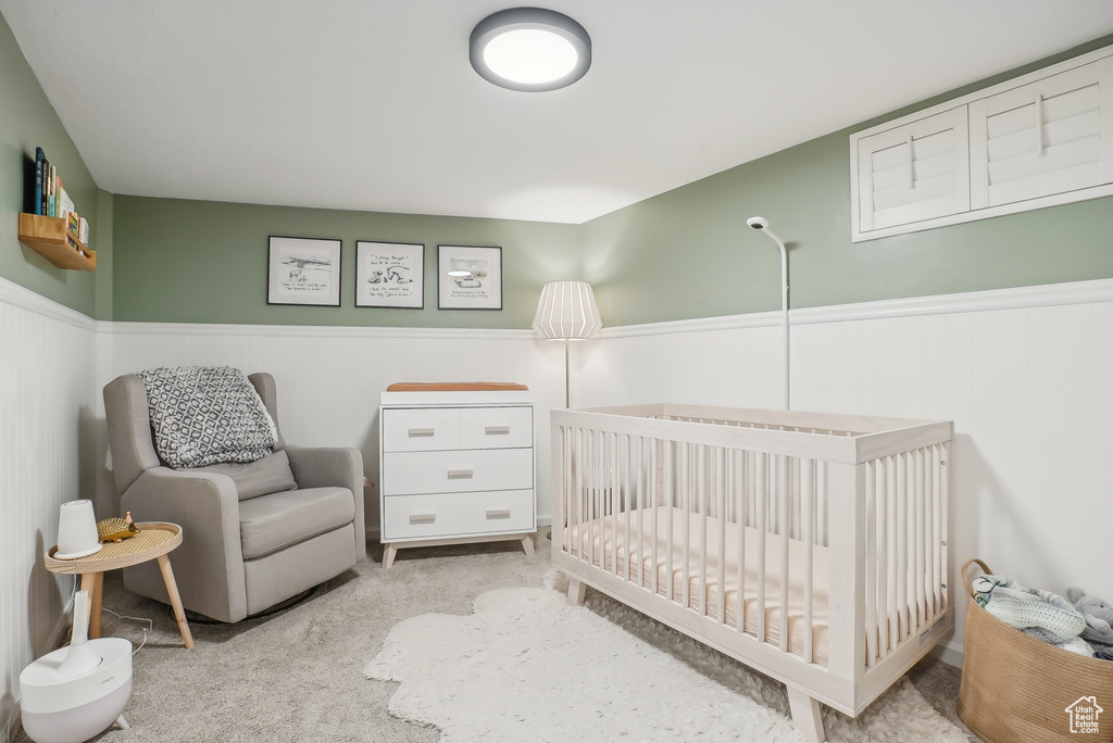 Bedroom featuring a crib and light carpet