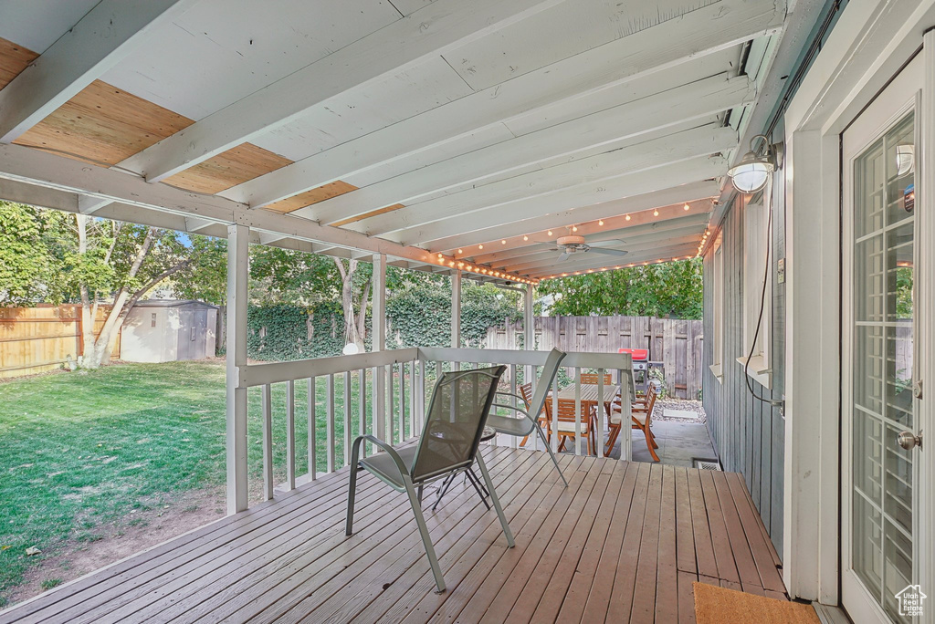 Wooden terrace featuring a storage shed and a lawn