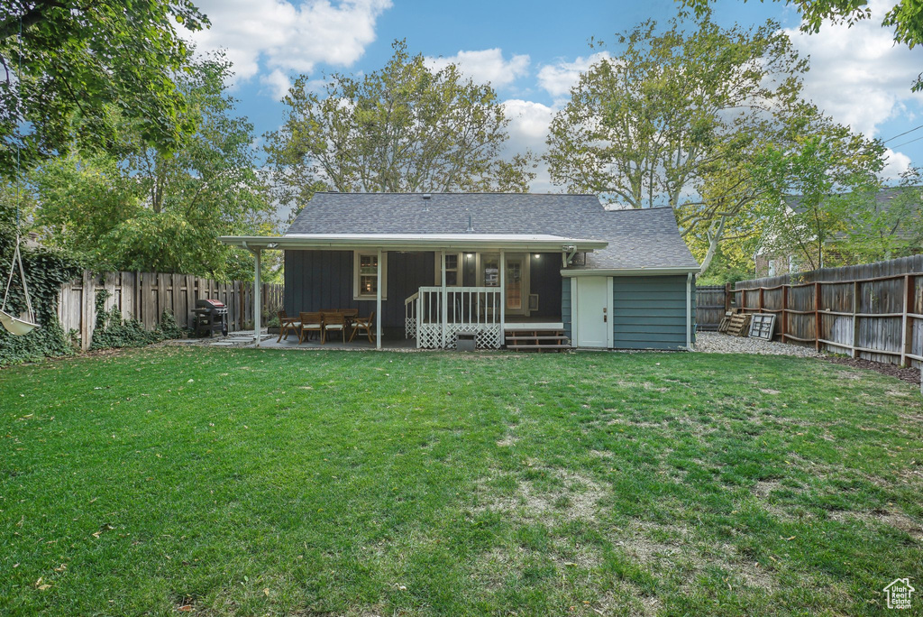 Rear view of house with a lawn and a patio