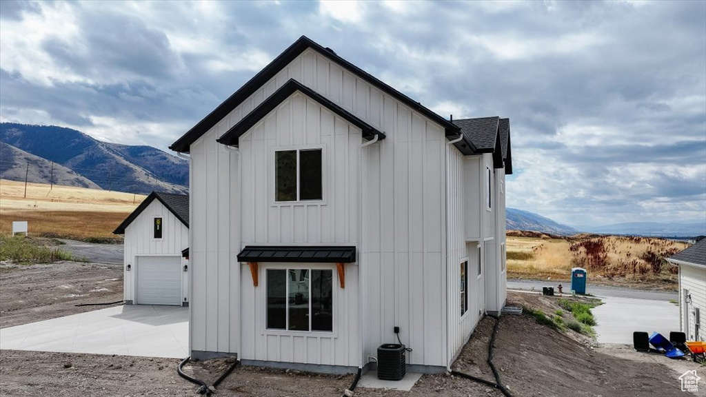 Back of property featuring central AC, a mountain view, and a garage