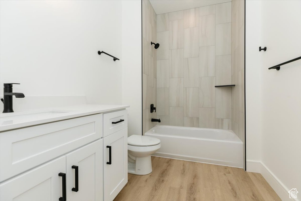 Full bathroom with wood-type flooring, tiled shower / bath, vanity, and toilet