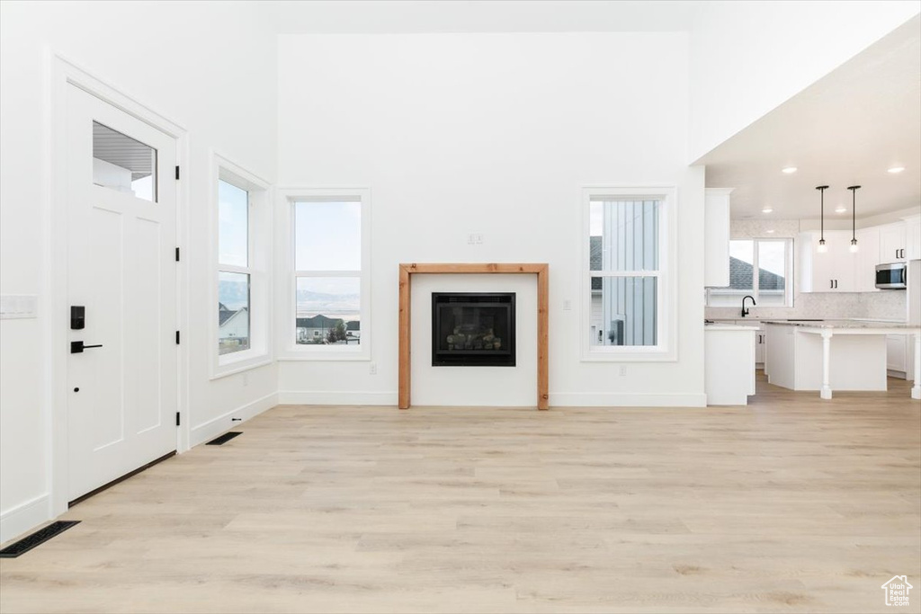 Unfurnished living room featuring a high ceiling and light hardwood / wood-style floors