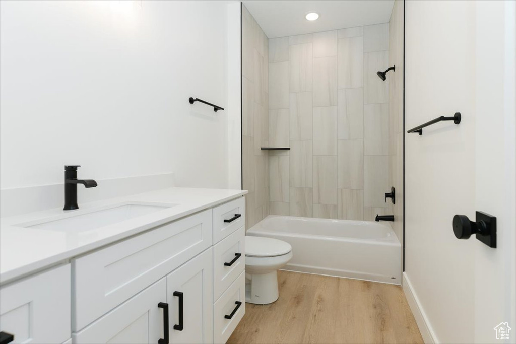 Full bathroom featuring tiled shower / bath, vanity, toilet, and hardwood / wood-style flooring