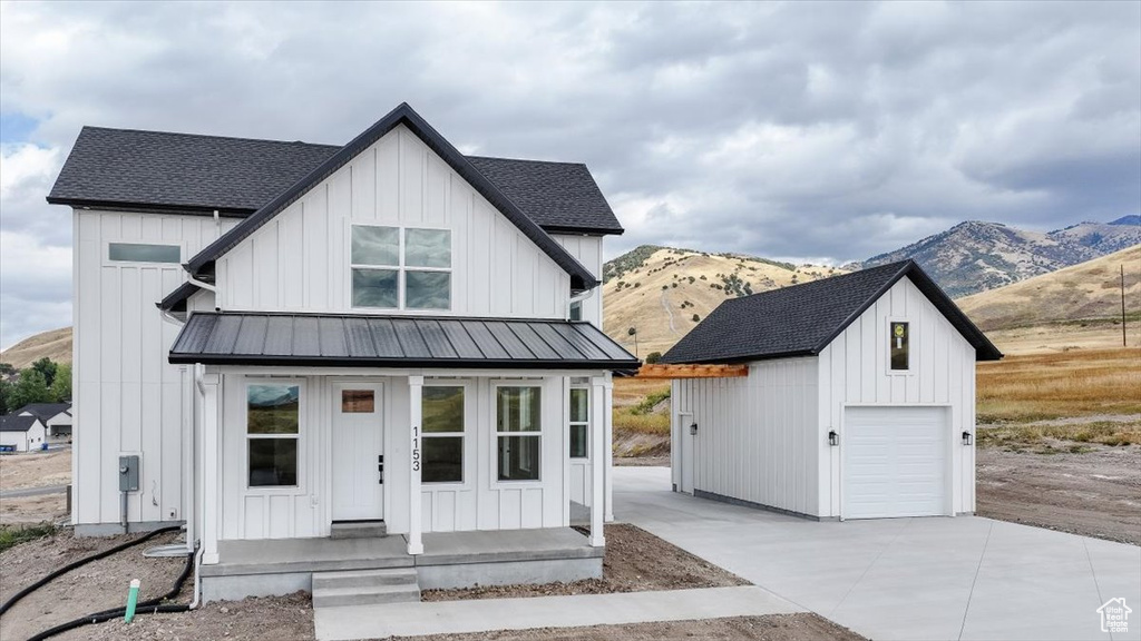 Modern farmhouse featuring a mountain view, a garage, and an outdoor structure