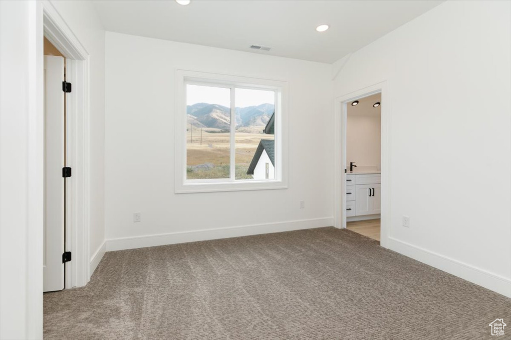 Unfurnished bedroom featuring light colored carpet and ensuite bathroom