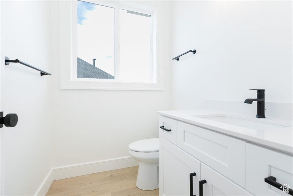 Bathroom featuring hardwood / wood-style flooring, vanity, and toilet