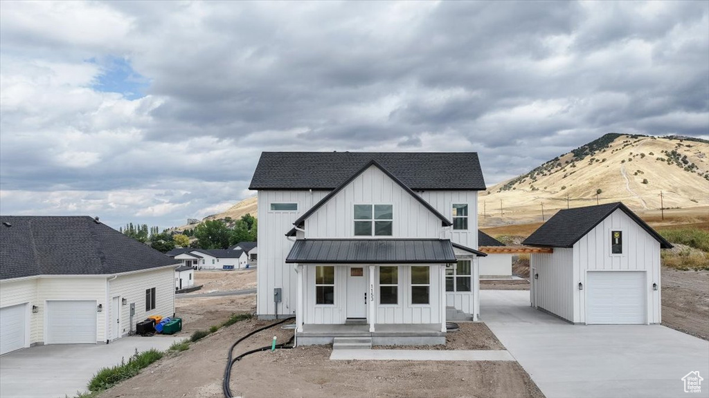 Modern inspired farmhouse featuring a mountain view, an outdoor structure, a garage, and a porch