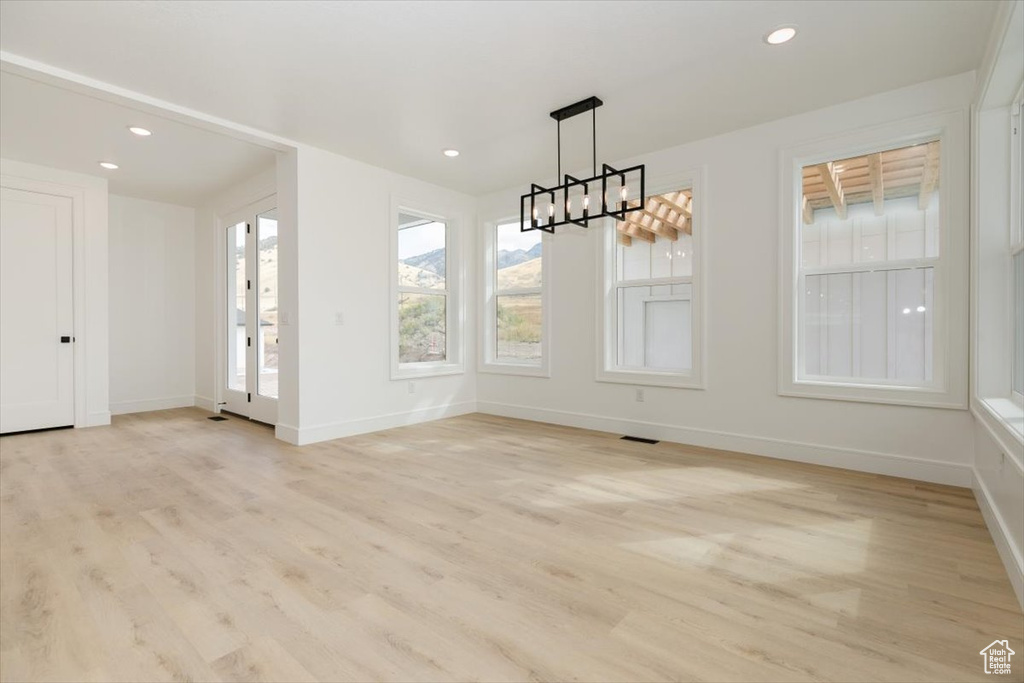 Unfurnished dining area with a notable chandelier and light wood-type flooring