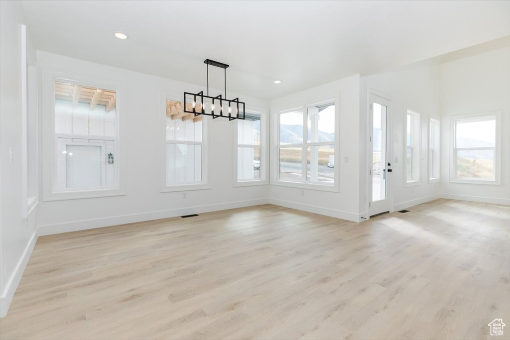 Unfurnished dining area with a chandelier and light hardwood / wood-style floors