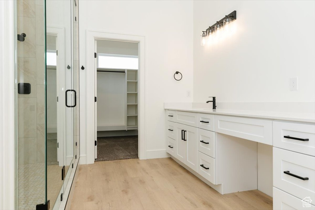 Bathroom featuring hardwood / wood-style flooring, a shower with door, and vanity