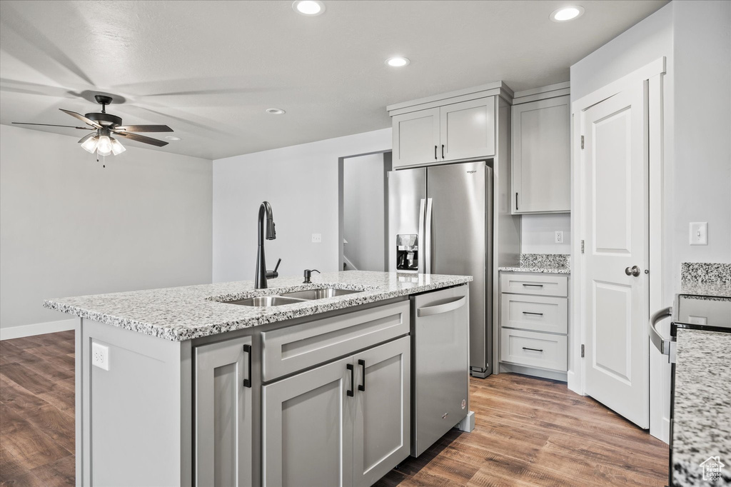 Kitchen with gray cabinets, dark wood-type flooring, a center island with sink, sink, and dishwasher