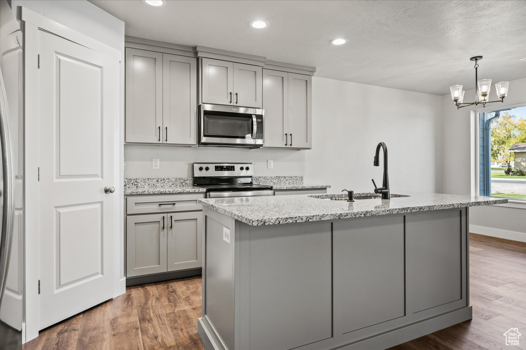 Kitchen with a kitchen island with sink, appliances with stainless steel finishes, sink, and dark hardwood / wood-style flooring