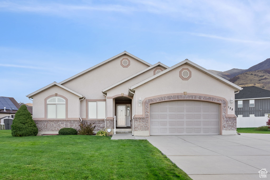 Ranch-style house featuring a front lawn, a mountain view, and a garage