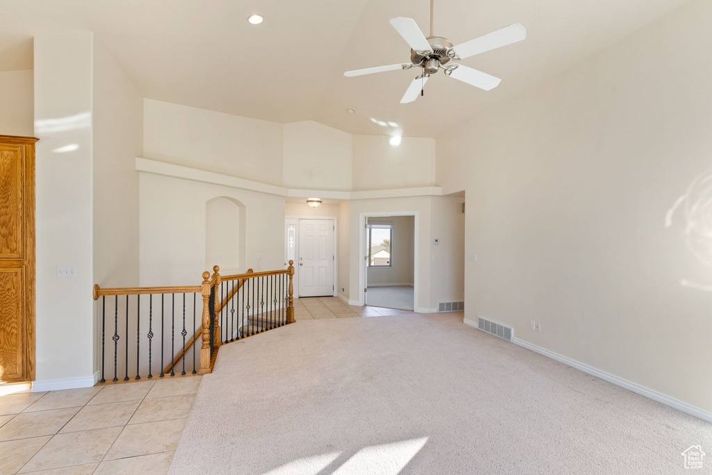 Tiled empty room featuring a towering ceiling and ceiling fan