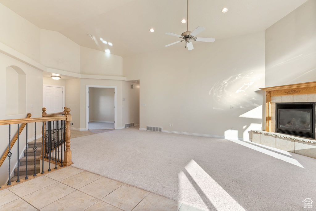 Living room featuring light carpet, a fireplace, high vaulted ceiling, and ceiling fan