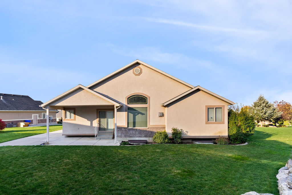 Rear view of house with a yard and a patio