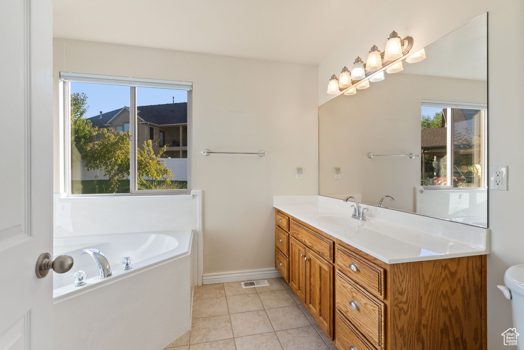 Bathroom with vanity, a tub to relax in, and tile patterned flooring