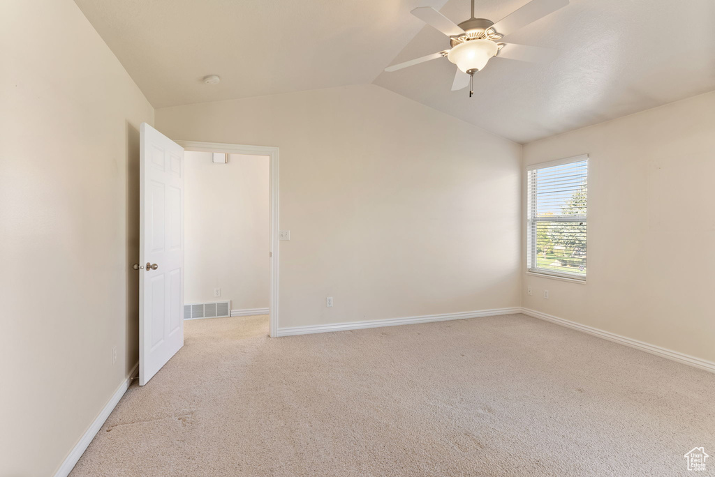 Carpeted empty room featuring lofted ceiling and ceiling fan