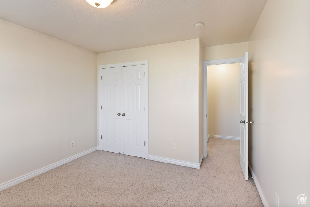 Unfurnished bedroom with a closet and light colored carpet