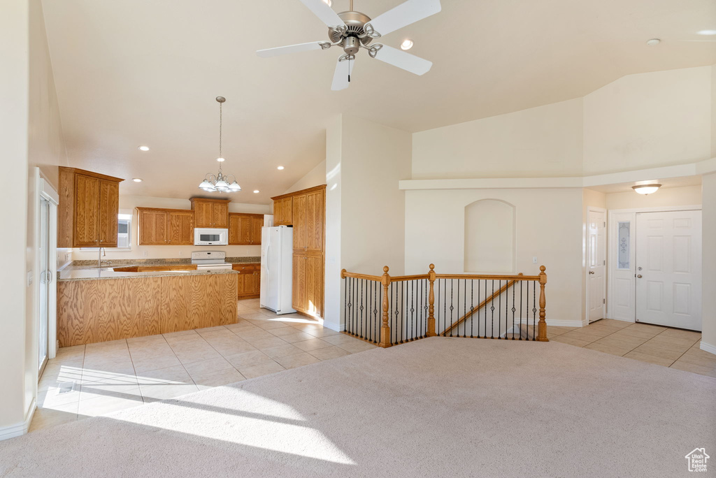 Kitchen featuring pendant lighting, white appliances, light colored carpet, and kitchen peninsula