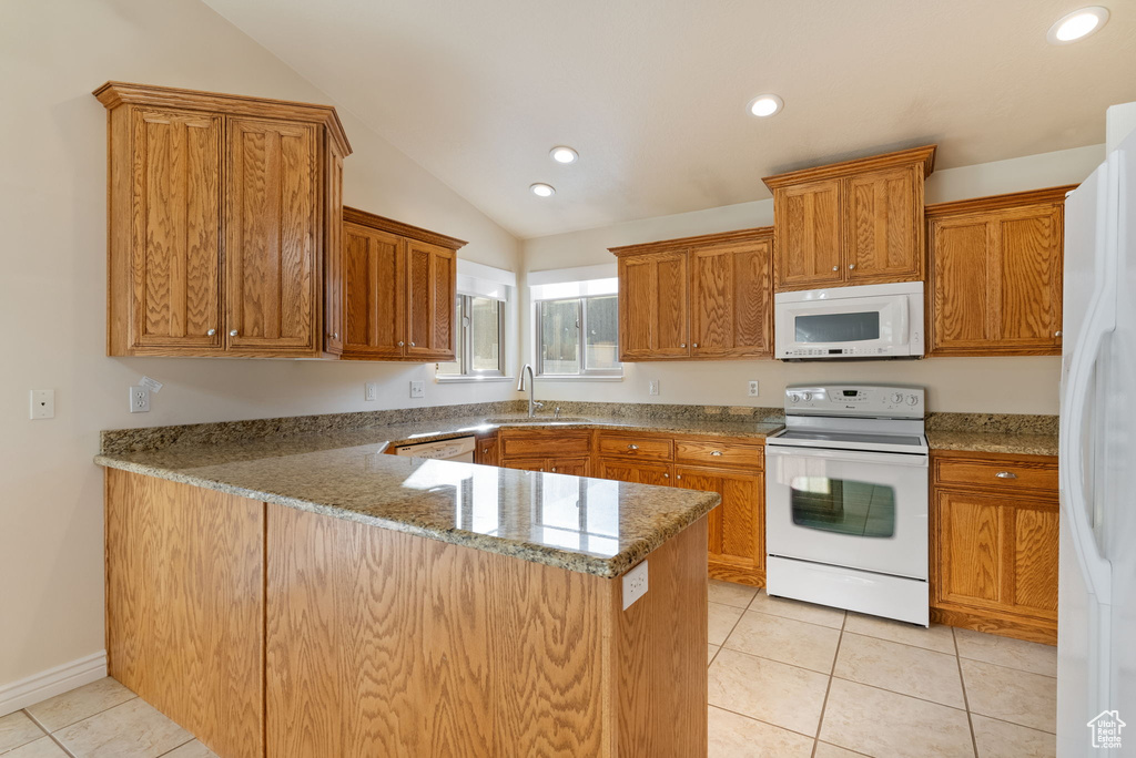 Kitchen with lofted ceiling, white appliances, light tile patterned floors, and kitchen peninsula