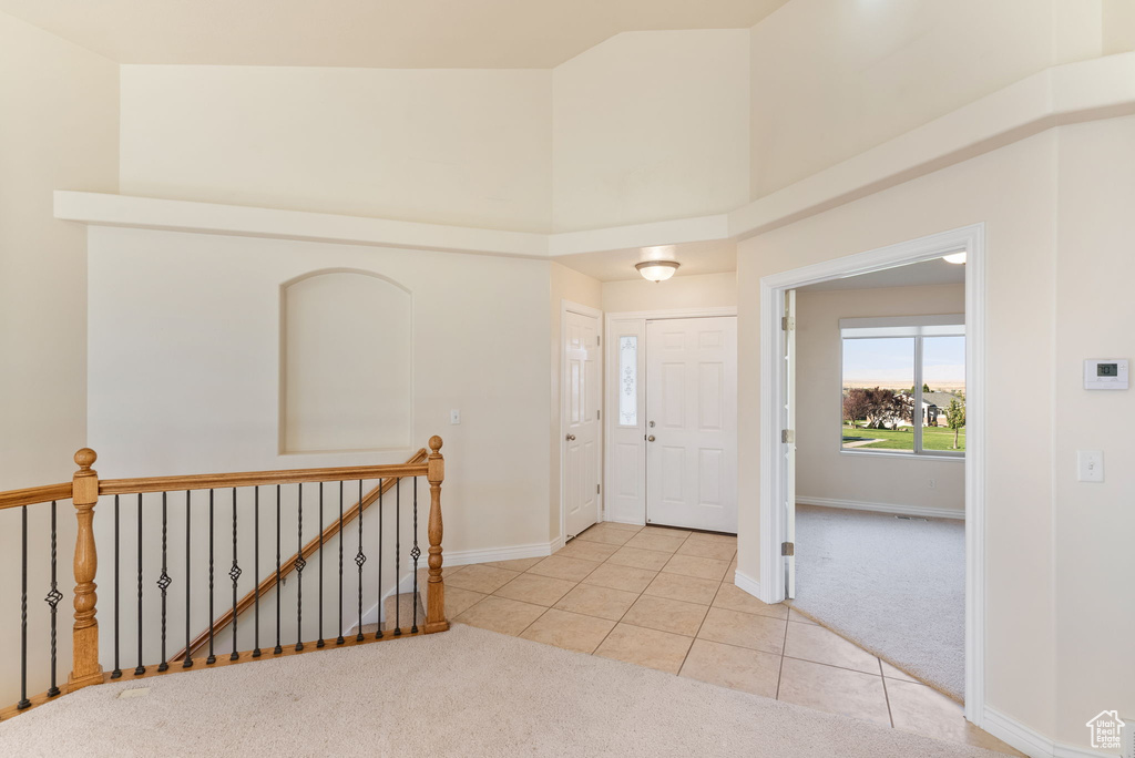 Foyer featuring light carpet and a towering ceiling