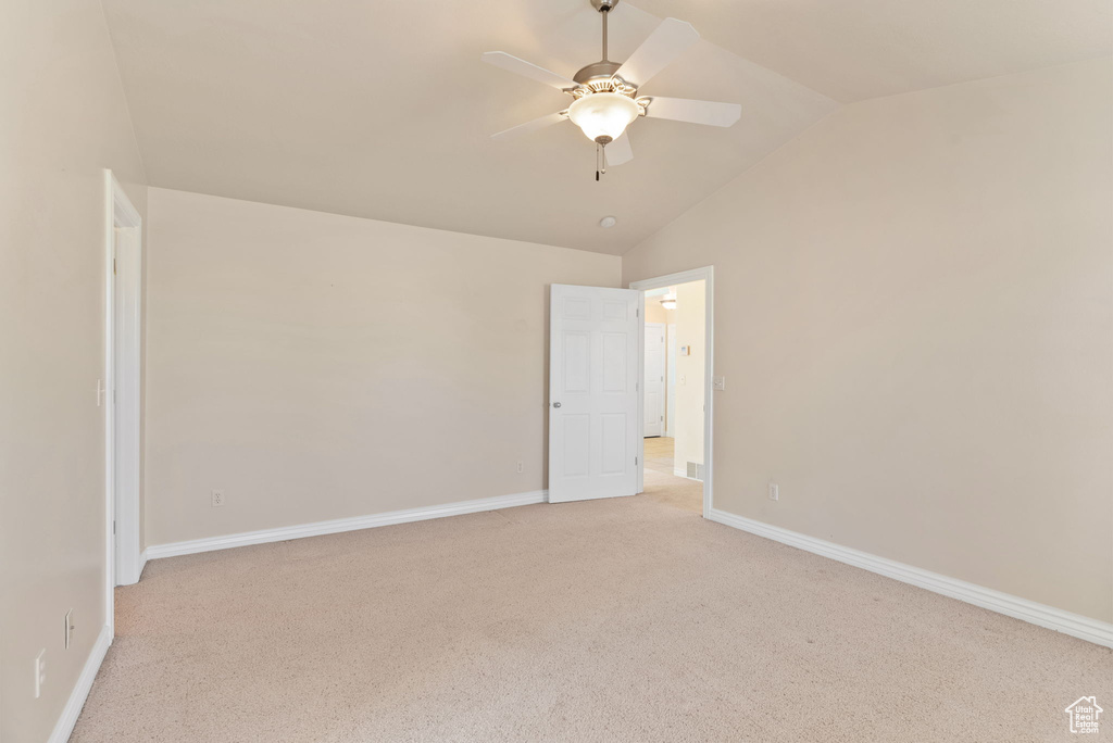 Empty room featuring ceiling fan, light colored carpet, and lofted ceiling